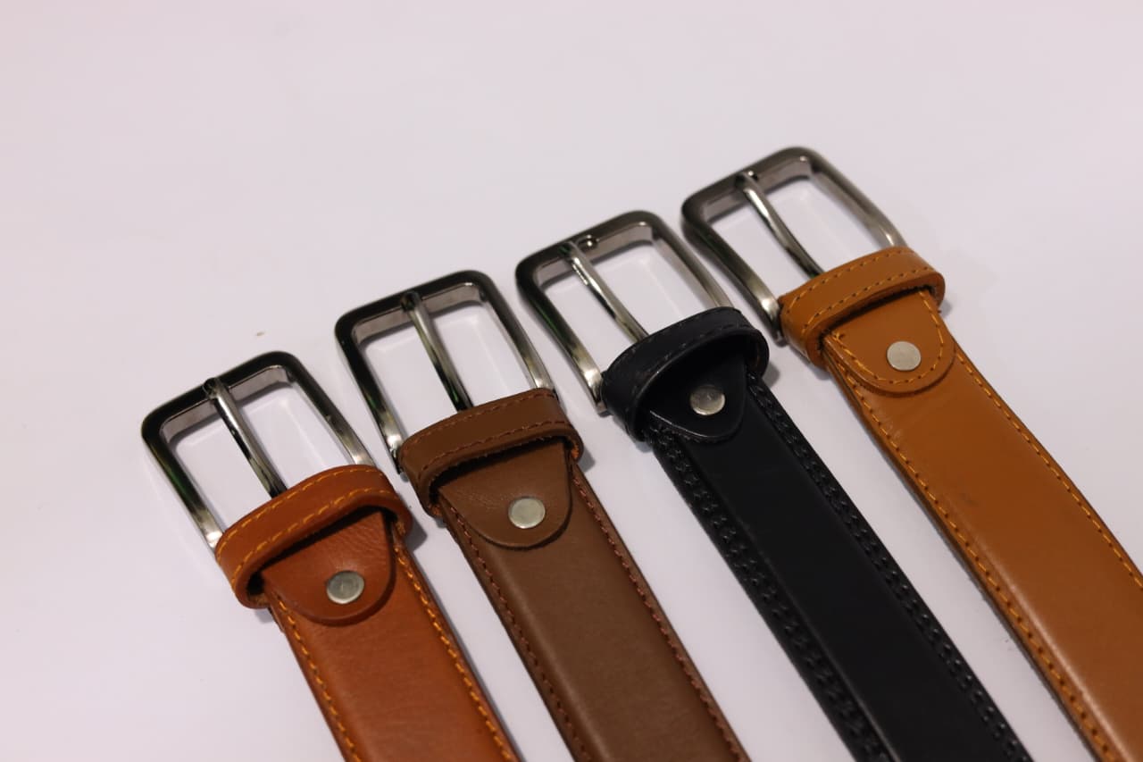 Four leather belts with metal buckles on a white background