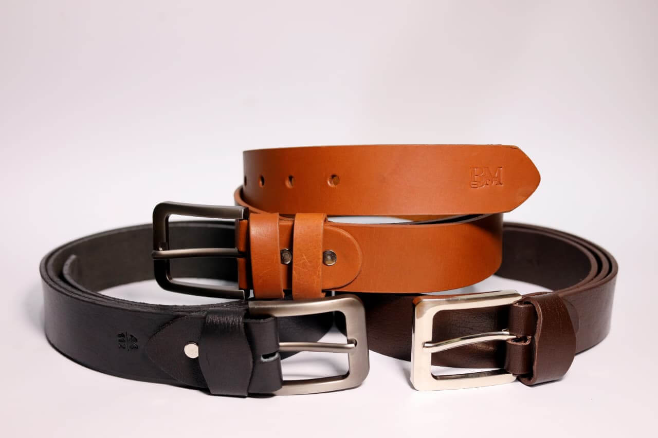 Three leather belts in black, brown, and tan with silver buckles on a light gray background.