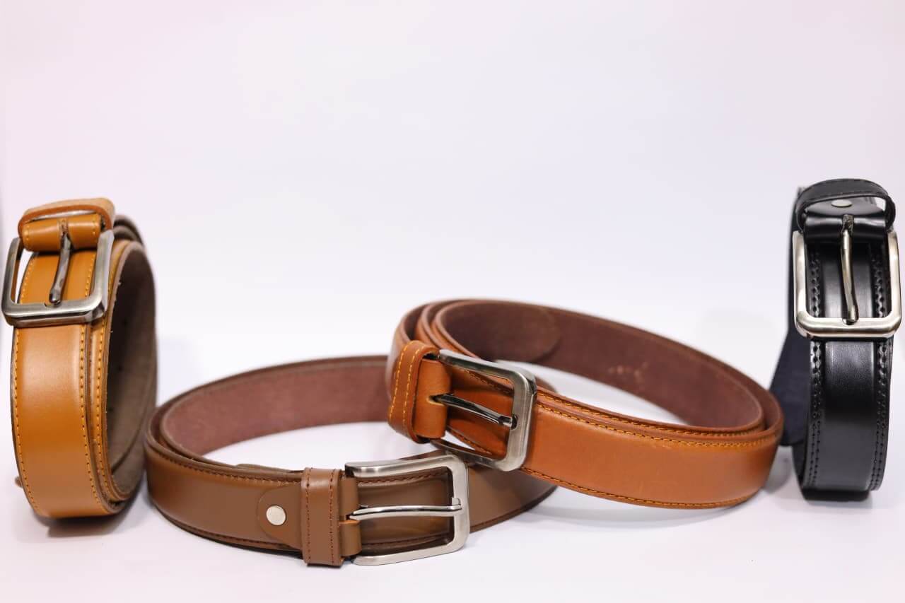 Three belts in brown and black with metal buckles on a white background
