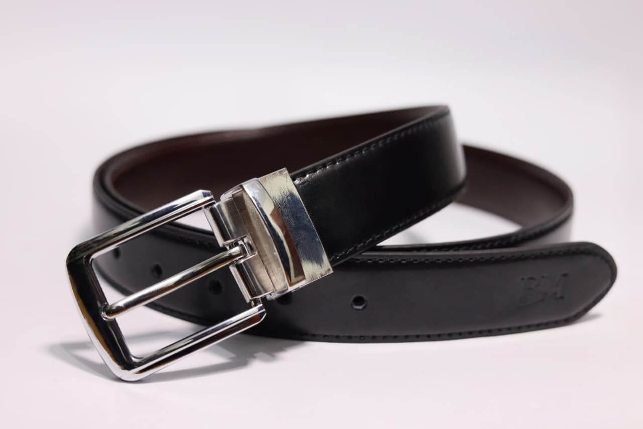 Brown leather belt with silver buckle on a light gray background