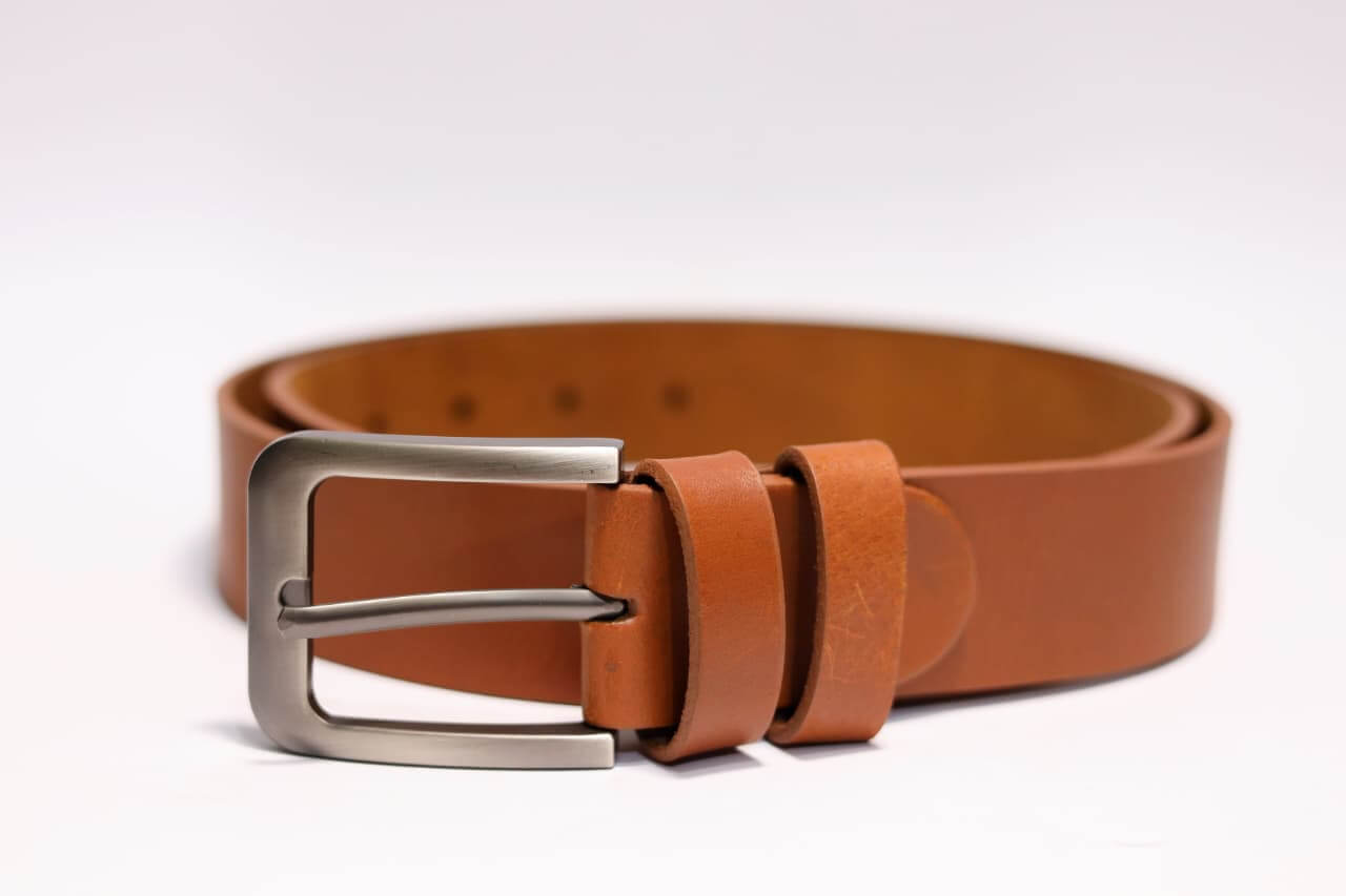 Brown leather belt with a silver buckle on a white background